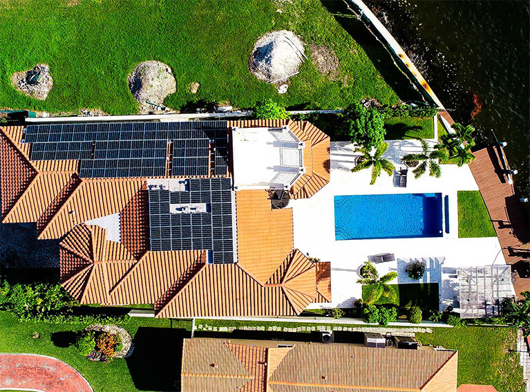 solar panels on orange shingled house with pool by the water in florida