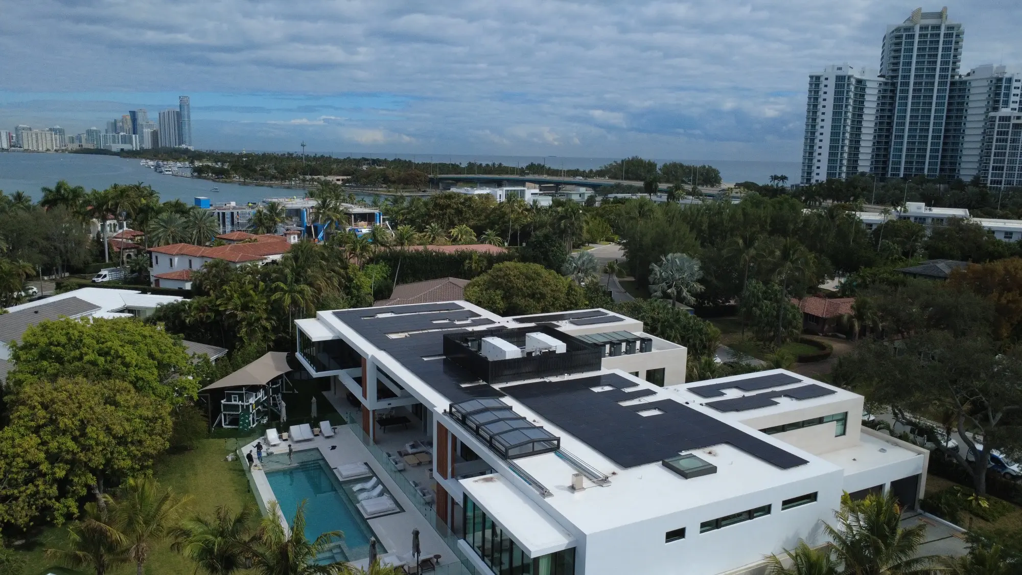 Aerial view of a South Florida home with rooftop solar panels under a cloudy sky